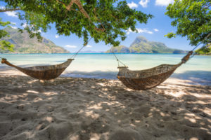 El Nido, Palawan, Philippines. Bamboo hammocks on shore in the shade. Beautiful tropical lagoon with epic Cadlao island in background. El Nido, Palawan, Philippines. Bamboo hammocks on shore in the shade. Beautiful tropical lagoon with epic Cadlao island in background.